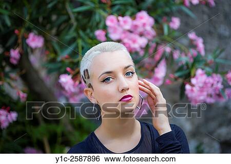 Stock Photograph - Portrait of young woman before Violet flowers. Fotosearch