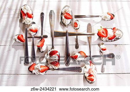 Stock Image - Presentation of the strawberries with cream spoons on various.. Fotosearch