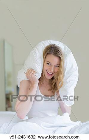 Pretty blonde woman in bed with pillow over her head, smiling at camera View Large Photo Image Stock Image - Pretty blonde woman in bed with pillow over her head, smiling at camera. Fotosearch