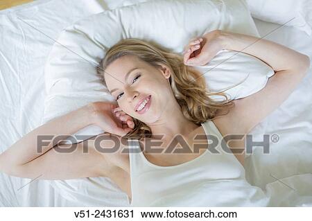 Pretty blonde woman waking up and stretching in bed smiling at camera View Large Photo Image Stock Image - Pretty blonde woman waking up and stretching in bed smiling at camera. Fotosearch
