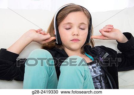 pretty little girl listening to music with a headset and stopping her ears with her fingers for concentration View Large Photo Image Stock Image - pretty little girl listening to music with a headset and stopping her ears with her fingers for concentration. Fotosearch