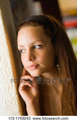 Stock Image - Pretty young woman next to a window. Fotosearch
