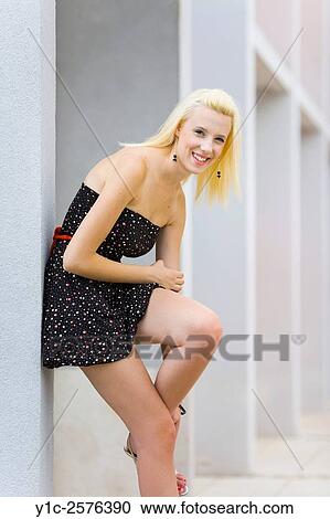 Stock Image - Pretty young woman smiling with knee up. Fotosearch