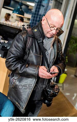 Rotterdam, Netherlands. Balding, middle aged photographer consulting his smartphone for messages. View Large Photo Image Stock Photograph - Rotterdam, Netherlands. Balding, middle aged photographer consulting his smartphone for messages.. Fotosearch