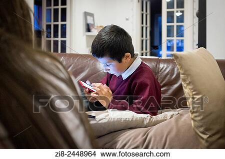 Schoolboy, 7, playing games on smart phone. View Large Photo Image Picture - Schoolboy, 7, playing games on smart phone.. Fotosearch