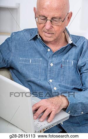 Senior man using a laptop computer at home View Large Photo Image Stock Image - Senior man using a laptop computer at home. Fotosearch