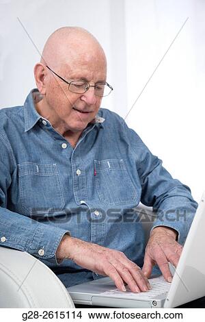 Senior man using and writing on a white laptop computer View Large Photo Image Picture - Senior man using and writing on a white laptop computer. Fotosearch