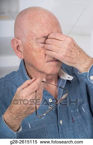 Senior man with eyes shut, rubbing his eyes because of fatigue or headache, and holding his glasses in one hand View Large Photo Image Stock Photography - Senior man with eyes shut, rubbing his eyes because of fatigue or headache, and holding his glasses in one hand. Fotosearch