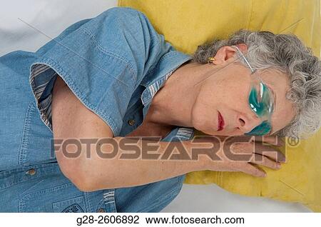 Senior woman with grey hair, with a blue Gel hot or cold mask upon her eyes, taking a nap, to relieve her headache View Large Photo Image Stock Image - Senior woman with grey hair, with a blue Gel hot or cold mask upon her eyes, taking a nap, to relieve her headache. Fotosearch