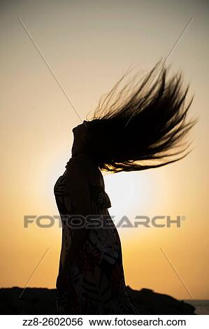 Silhouette of a young woman flicking hair hair against the sunset. View Large Photo Image Stock Photograph - Silhouette of a young woman flicking hair hair against the sunset.. Fotosearch