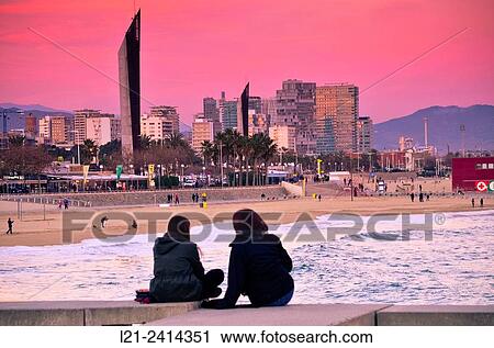 Silhouette of two sitting people back contemplating a coastal cityscape at sunset. Beach and sea. Buildings and skyscrapers skyline. Diagonal Mar, Barcelona, Catalonia, Spain. View Large Photo Image Stock Image - Silhouette of two sitting people back contemplating a coastal cityscape at sunset. Beach and sea. Buildings and skyscrapers skyline. Diagonal Mar, Barcelona, Catalonia, Spain.. Fotosearch