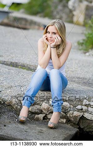 Stock Image - Sitting alone outside young woman. Fotosearch