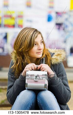 Stock Photo - Sitting with a box bag in hand young woman expecting someone. Fotosearch
