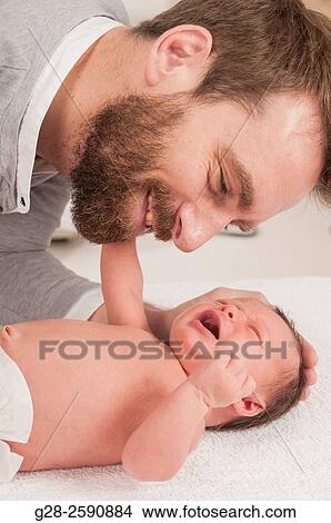 Smiling happy father bending over his crying baby boy, 2 weeks old, to calm and comfort him View Large Photo Image Picture - Smiling happy father bending over his crying baby boy, 2 weeks old, to calm and comfort him. Fotosearch