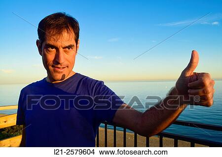 Picture - Smiling man saying ok, thumbs up.. Fotosearch