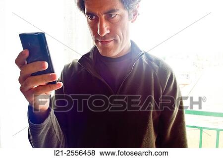 Smiling man with casual clothes using a mobile phone, consulting his smartphone. View Large Photo Image Stock Photo - Smiling man with casual clothes using a mobile phone, consulting his smartphone.. Fotosearch