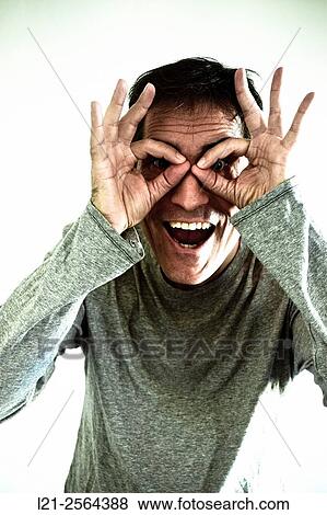 Smiling man with hands imitating glasses or some binoculars. View Large Photo Image Stock Photo - Smiling man with hands imitating glasses or some binoculars.. Fotosearch