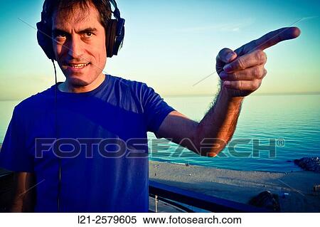 Smiling man with headphones pointing the finger in any direction. View Large Photo Image Stock Photography - Smiling man with headphones pointing the finger in any direction.. Fotosearch