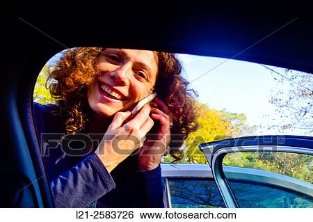 Smiling woman talking with her mobile phone before entering inside her car. View Large Photo Image Stock Photograph - Smiling woman talking with her mobile phone before entering inside her car.. Fotosearch