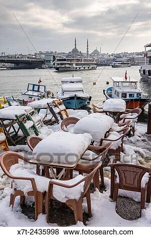 Snow covered cafe chairs on Karakoy waterfront, looking across the Golden Horn toward the Yeni mosque at Eminonu and the Istanbul skyline. Istanbul, Turkey. View Large Photo Image Stock Photo - Snow covered cafe chairs on Karakoy waterfront, looking across the Golden Horn toward the Yeni mosque at Eminonu and the Istanbul skyline. Istanbul, Turkey.. Fotosearch