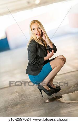 Picture - Squatting teen girl with cellphone in hand. Fotosearch