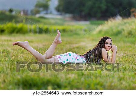 Stock Image - Stock Photo - Playful country-girl lying in greenfield. Fotosearch