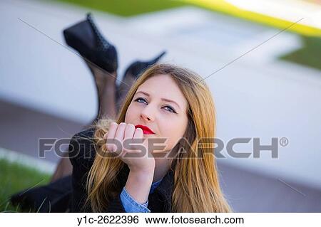 Stock Photograph - Teen girl lying on meadow field looking up day-dreaming. Fotosearch
