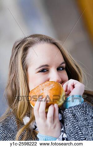 Stock Image - Teen girl peeking behind donut with messy nose. Fotosearch