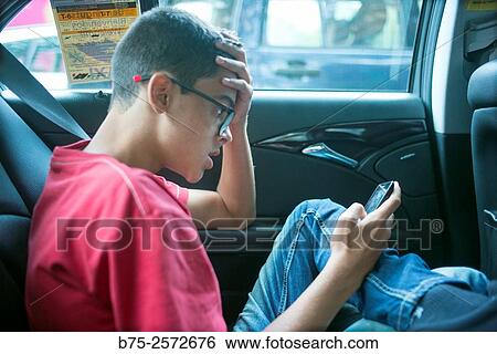 Teenage boy, manipulating a cell phone in a cab, with expression of surprise. Barcelona, Catalonia, Spain View Large Photo Image Stock Photograph - Teenage boy, manipulating a cell phone in a cab, with expression of surprise. Barcelona, Catalonia, Spain. Fotosearch