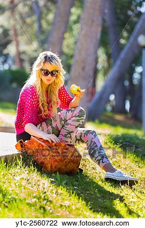 Stock Image - Teenager girl in park eating apple in hand. Fotosearch