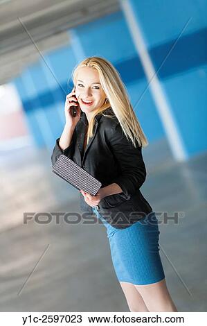 Stock Image - Teenager girl talking using cell-phone looking at camera. Fotosearch