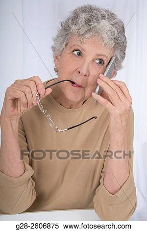Thoughtful senior woman with grey hair, biting her glasses and using a mobile phone View Large Photo Image Stock Photography - Thoughtful senior woman with grey hair, biting her glasses and using a mobile phone. Fotosearch
