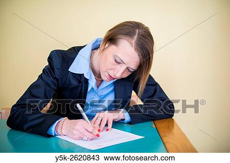 Stock Image - Tilburg, Netherlands. Attractive blonde woman signing a model release before a studio shoot.. Fotosearch
