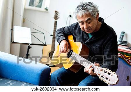 Tilburg, Netherlands. Middle aged man playing acoustic guitar in his living room. View Large Photo Image Picture - Tilburg, Netherlands. Middle aged man playing acoustic guitar in his living room.. Fotosearch
