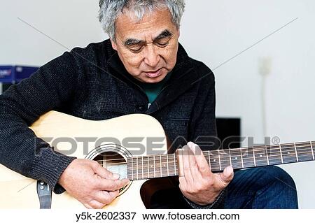 Tilburg, Netherlands. Middle aged man playing acoustic guitar in his living room. View Large Photo Image Stock Photo - Tilburg, Netherlands. Middle aged man playing acoustic guitar in his living room.. Fotosearch