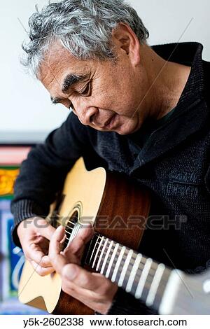 Tilburg, Netherlands. Middle aged man playing acoustic guitar in his living room. View Large Photo Image Stock Photo - Tilburg, Netherlands. Middle aged man playing acoustic guitar in his living room.. Fotosearch