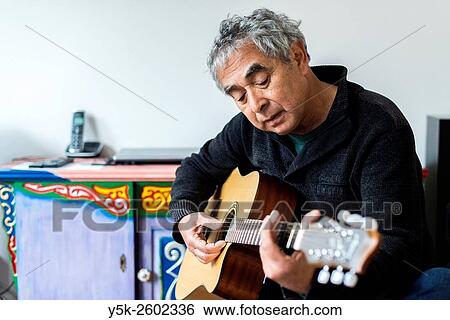 Tilburg, Netherlands. Middle aged man playing acoustic guitar in his living room. View Large Photo Image Stock Photograph - Tilburg, Netherlands. Middle aged man playing acoustic guitar in his living room.. Fotosearch