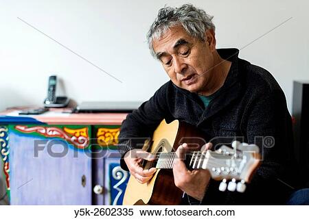 Tilburg, Netherlands. Middle aged man playing acoustic guitar in his living room. View Large Photo Image Stock Photography - Tilburg, Netherlands. Middle aged man playing acoustic guitar in his living room.. Fotosearch