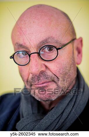 Tilburg, Netherlands. Studio-portrait of a balding man wearing glasses, in front of a yellow background, having hidden thoughts. View Large Photo Image Stock Photography - Tilburg, Netherlands. Studio-portrait of a balding man wearing glasses, in front of a yellow background, having hidden thoughts.. Fotosearch