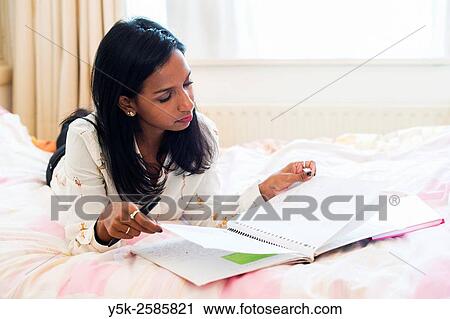 Tilburg, Netherlands. Young, dark skinned woman reading back from her diary, whily stretched out on her bed. View Large Photo Image Stock Image - Tilburg, Netherlands. Young, dark skinned woman reading back from her diary, whily stretched out on her bed.. Fotosearch