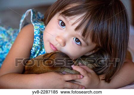 Stock Photography - Toddler girl holding her puppy dog.. Fotosearch