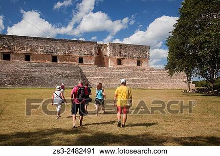 Stock Image - Tourists in Uxmal Ruins near the Quadrangle Of The Nuns, Yucatan Province, Mexico, Central America.. Fotosearch