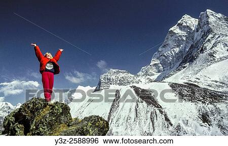 Stock Photograph - Trekker relishes the beauty of the Khumbu Himal, North Ridge Ama Dablam behind, Sagarmatha National Park, Nepal Himalaya.. Fotosearch