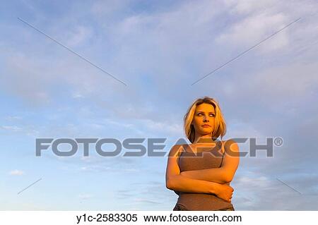 Stock Photography - Watching sunset young woman against sky. Fotosearch