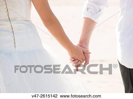 Wedding couple holding hands on their wedding day View Large Photo Image Stock Image - Wedding couple holding hands on their wedding day. Fotosearch
