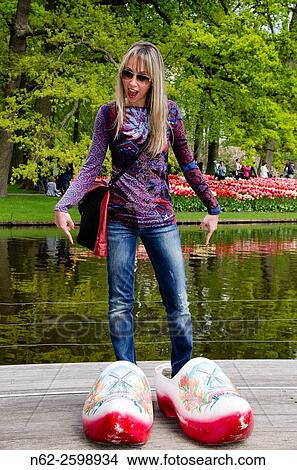 Picture - Woman amused indicates hooves giant who is wearing at park Keukenhof Amsterdam Netherlands.. Fotosearch