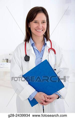 Picture - Woman doctor with stethoscope holding a blue folder and smiling. Fotosearch