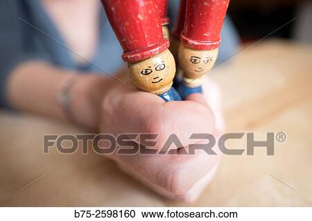 Stock Image - woman hand with two wooden dolls vintage game of a child looking at the camera.. Fotosearch