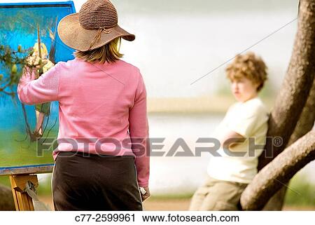 Stock Image - Woman painting boy. Fotosearch