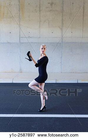 Woman poses with high-heel shoe in hand View Large Photo Image Stock Photo - Woman poses with high-heel shoe in hand. Fotosearch